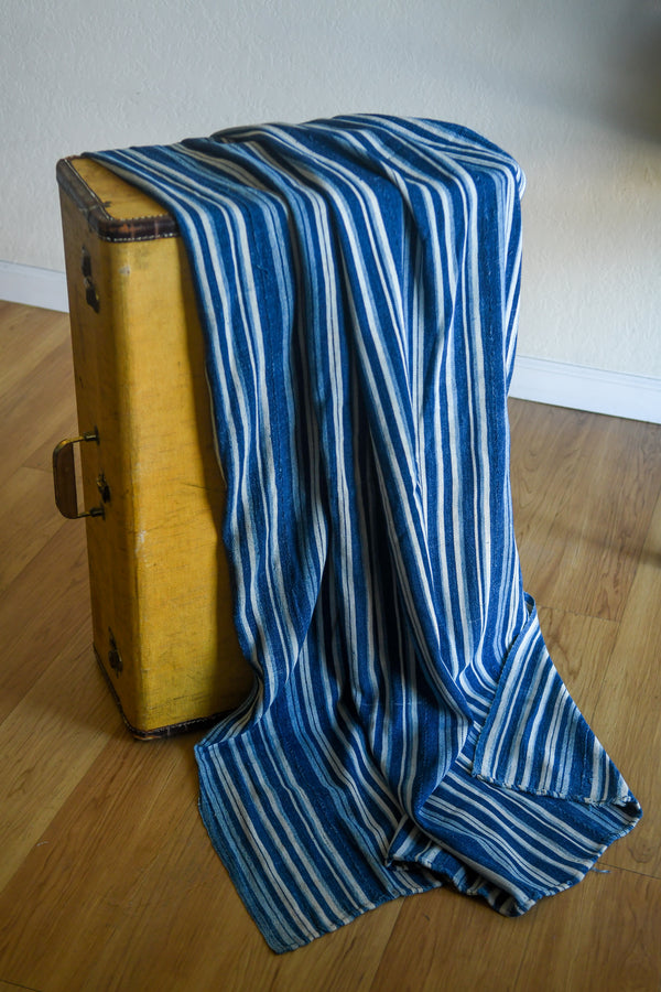 Handcrafted Textiles - Artisan Designed - Handcrafted African Art Textiles - Home Decor - Living Spaces - Mix Colors - Bold Patterns - Traditional Designs - African Culture - Add a unique piece to your home decor with this Indigo Dyed Stripe Woven Textile. This vintage faded blue cotton fabric is an authentic African Mossi textile, perfect for making a statement in any living space. Crafted with premium detail and care, it is suitable for both everyday use and collections. Length: 61 inches Width: 42 inches
