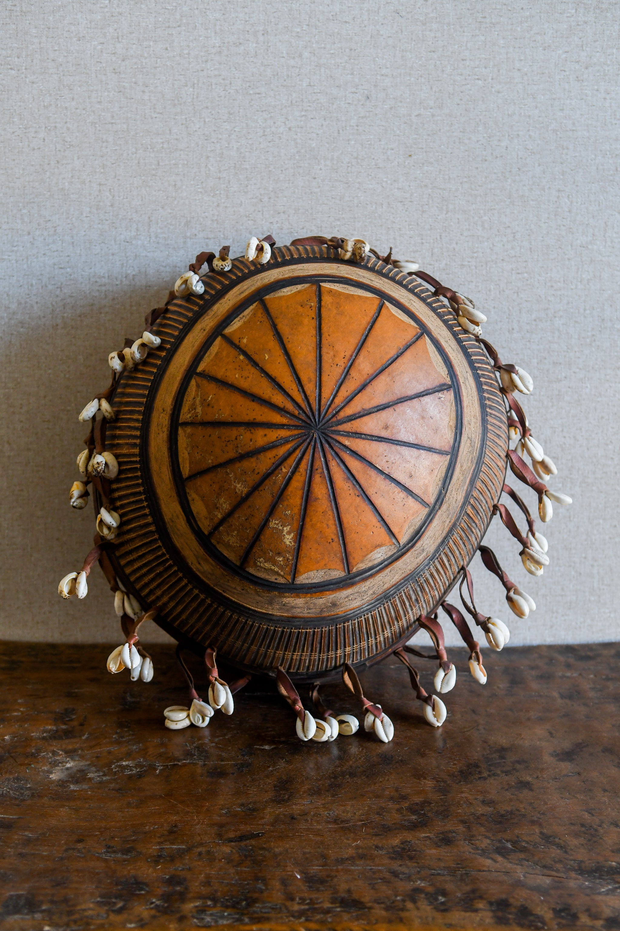 Tribal Objects - African Tribal Art - Ancient Ceremonial Art - Handcrafted Artifacts - Masks - Wood Sculptures - Iron Bronze Objects - Textiles - Art Pieces - African Folk Art - This African Calabash Bowl Cowrie Shell is a unique tribal instrument object, perfect for both home decor and collecting. It speaks to an ethnic, folk art aesthetic and is sure to be a conversation piece with guests. An excellent way to add a touch of culture and history to any space. Length: 13 inches Depth: 7 inches Width: 6