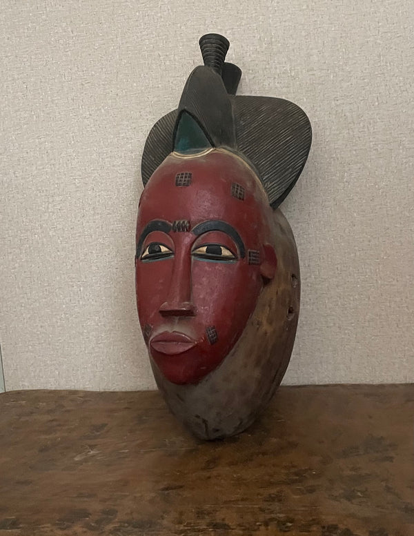 Handcrafted Masks - Artisan Designed - African Art Masks - Handcrafted Traditional - Home Decor - Business - Mask - Artwork - Any Space - African Art Mask - This Hand Carved Vintage Red Mask is a beautiful piece of African Baule art, perfect for home décor. Hand carved wood with exquisite detail, this mask is a traditional symbol of protection and power, adding a touch of history and culture to any space. Length: 16 Inches Width: 7.5 Inches